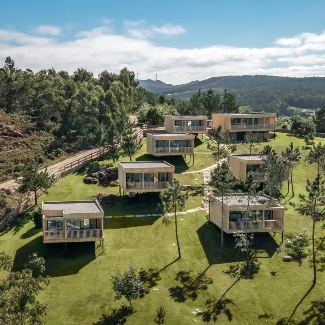 Completed glamping retreat with timber cabins set into a sea-and-mountain landscape