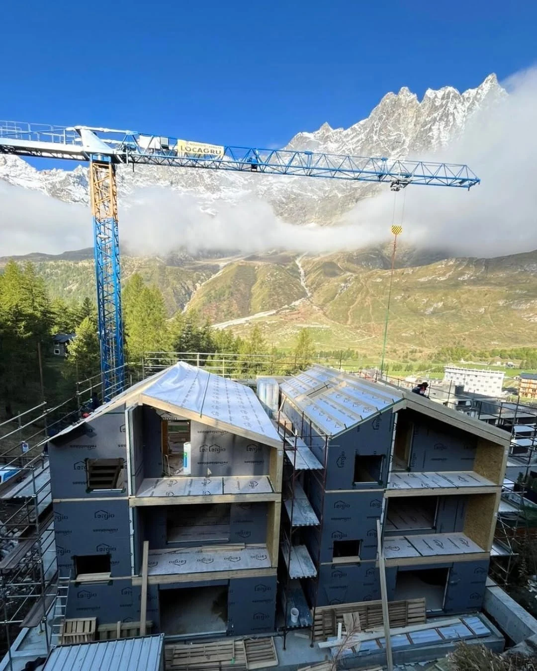 Prefabricated hotel units with coordinated walls and roof geometry beneath the Alpine mountains