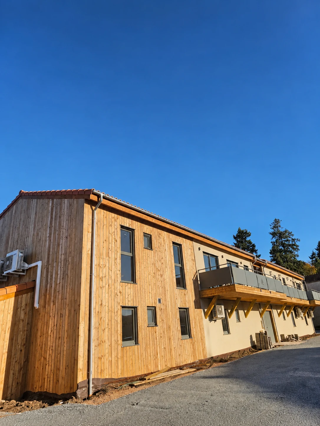 Facciata larga rivestita in legno con balcones in Village Seniors